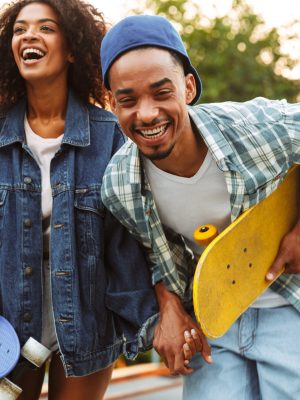 Portrait of an excited young african couple with skateboards having fun together at the skate park